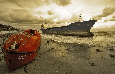Ship aground, with lifeboat on a beach. A mayday would have been called in this question.
